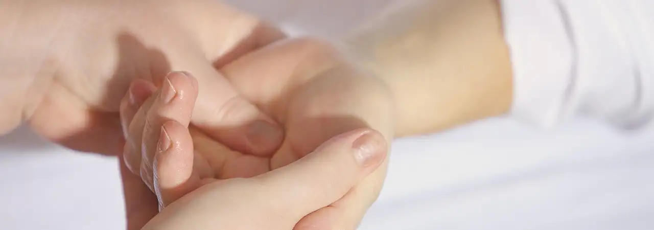 Zwei Hände bei einer Handmassage auf weißem Untergrund