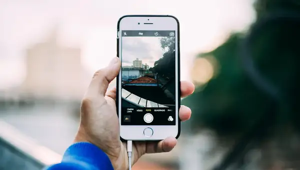 Hand hält ein Smartphone und fotografiert eine Straßenszene