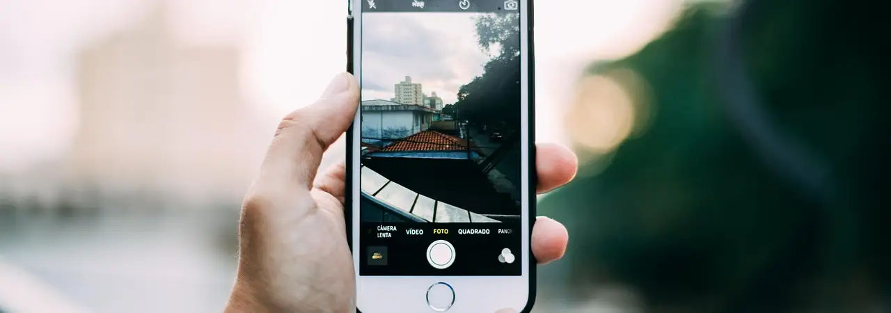 Hand hält ein Smartphone und fotografiert eine Straßenszene