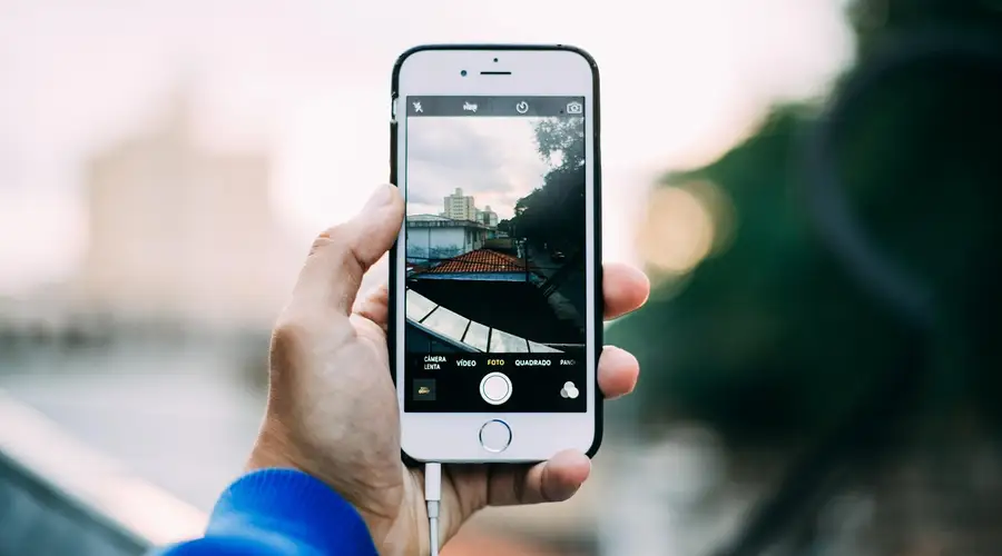 Hand hält ein Smartphone und fotografiert eine Straßenszene